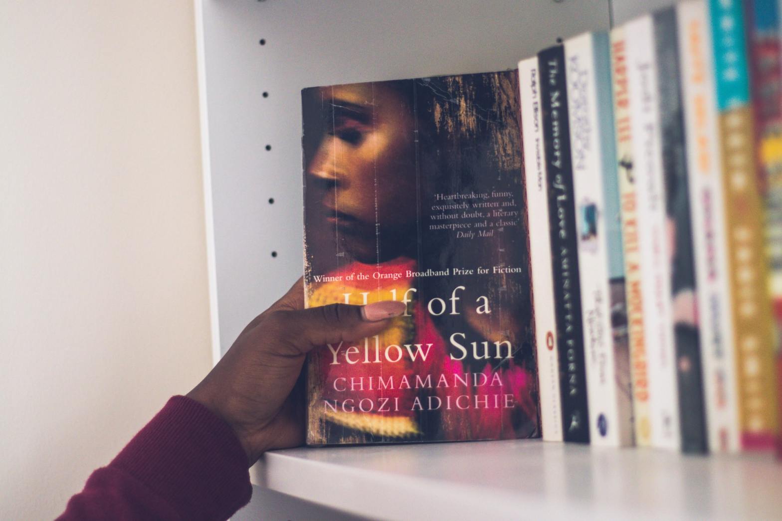 A person's hand picking a book from a shelf