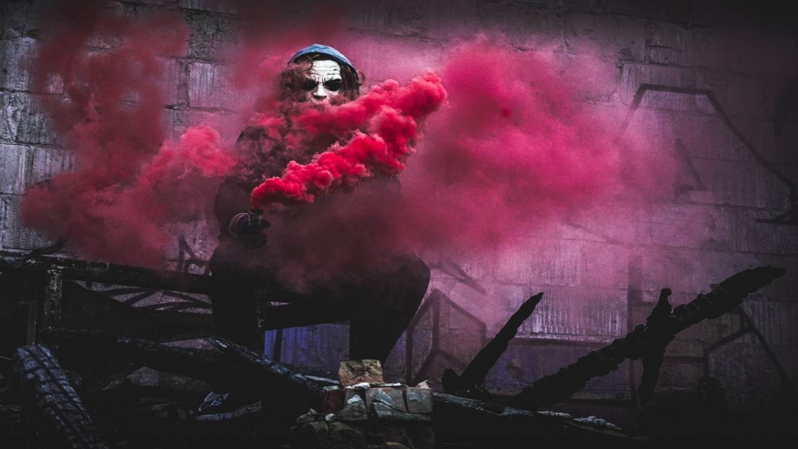 A man wearing a mask surrounded by pink smoke