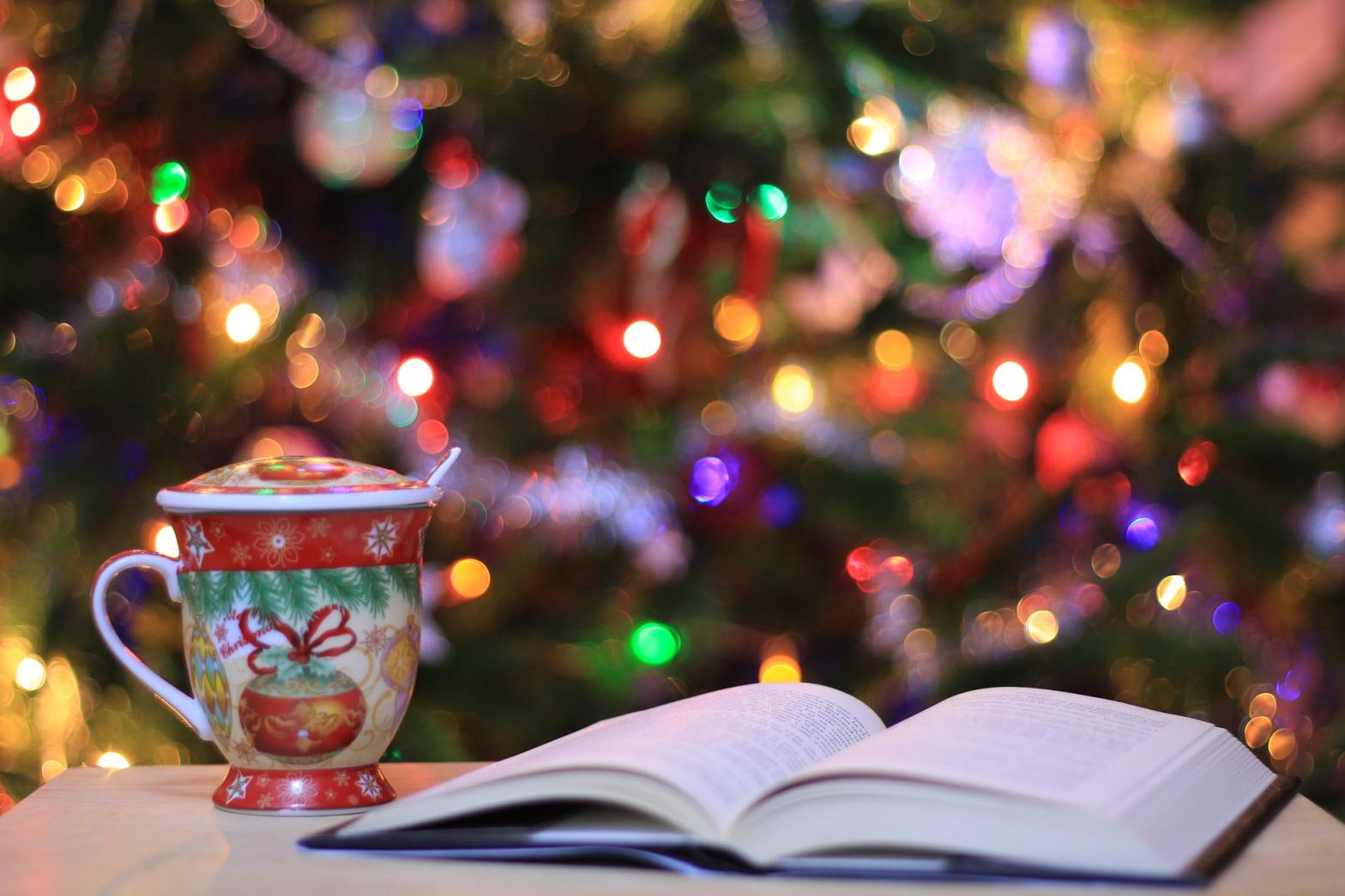 An open book beside a Christmas-theme mug