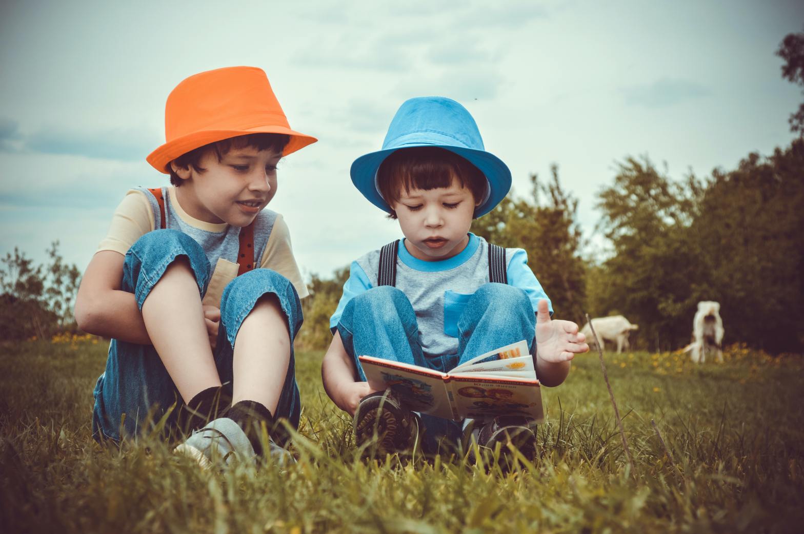 two kids reading on a grassfield