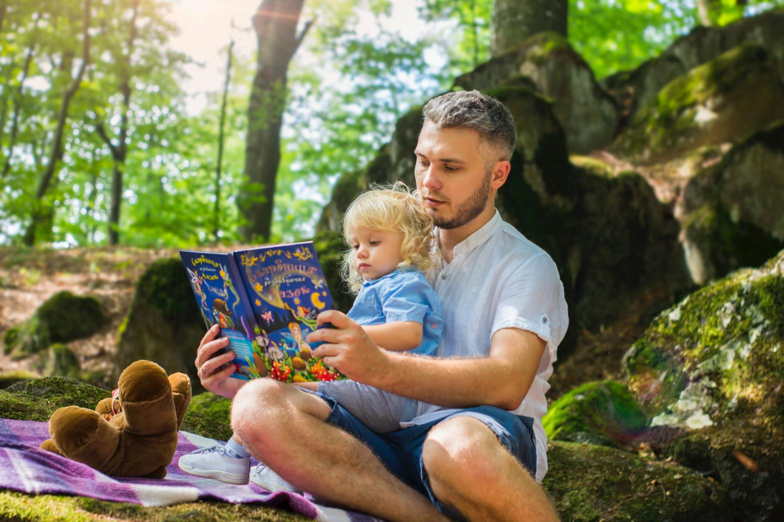 A father reading a story to his child in the woods.