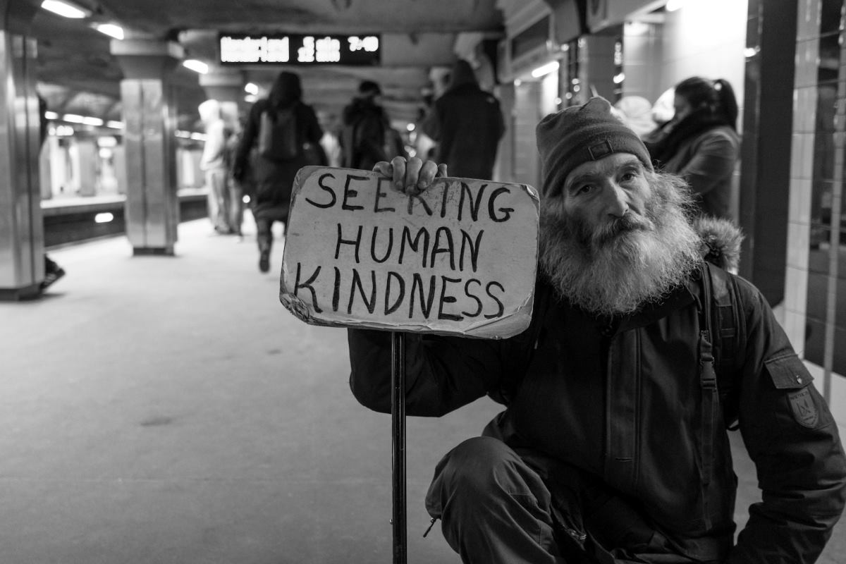 homeless man holding placard Jesus cares for the homeless